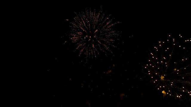 Slow motion large yellow and red balls fireworks with golden bright sparks in dark night sky.