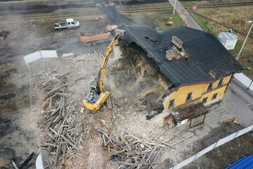 Yellow excavator destroys building. Heavy duty machine is demolishing a brick building. Demolition...