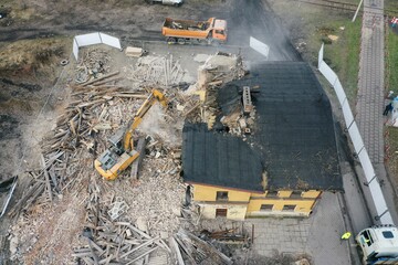 Yellow excavator destroys building. Heavy duty machine is demolishing a brick building. Demolition...
