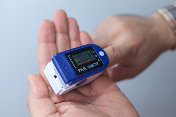 A man checks his oxygen level using an oximeter