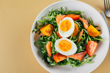 Healthy vegan salad of fresh tomato, arugula, salmon, egg and sesame. Keto diet menu. Top view.