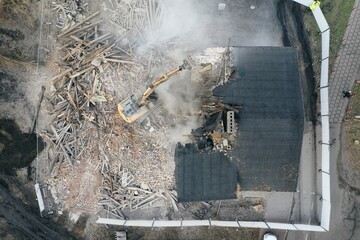 Yellow excavator destroys building. Heavy duty machine is demolishing a brick building. Demolition...