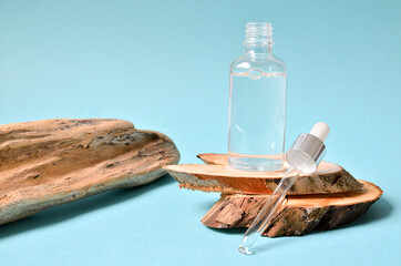 Cosmetic serum in white dropper bottles on natural wood. Blue background, natural skincare products concept.