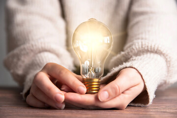 Female hand holding a shining light bulb, Great idea, innovation and inspiration, business concept background