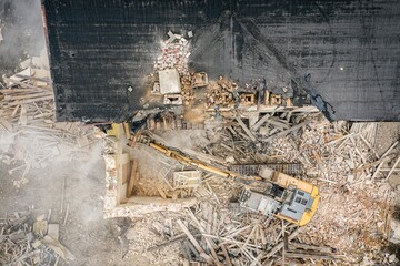 Yellow excavator destroys building. Heavy duty machine is demolishing a brick building. Demolition...