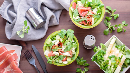 Summer mediterranean salad with ham and melon on dark wooden table top