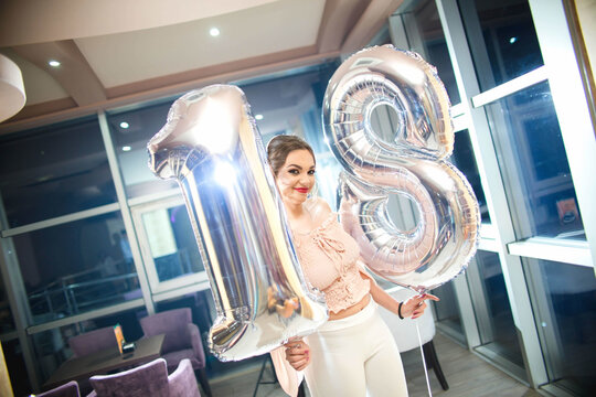 Portrait of a happy brunette female on her birthday party holding balloons in her hands - Powered by Adobe