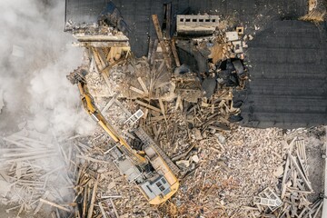 Yellow excavator destroys building. Heavy duty machine is demolishing a brick building. Demolition...