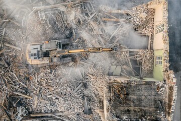 Yellow excavator destroys building. Heavy duty machine is demolishing a brick building. Demolition...
