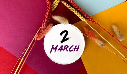March 2 on a white round object.Near the sprigs of wheat on a colorful bright background.Calendar for March .