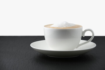 White cup with cappuccino on a black table, white background