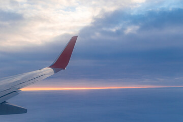 a view from a height above the clouds from the plane's window. part of an airplane wing in the frame
