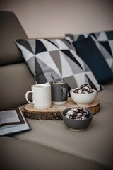 Festive breakfast for two, yummy homemade crinkle cookies and two cups of coffee on a sofa next to a book.