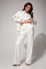 Sexy brunette woman luxury lifestyle bright makeup wear natural organic white silk suit pants...