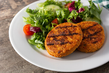 Delicious healthy chickpea burger and salad on wooden table