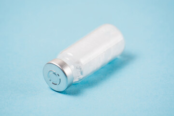 Ampoule with a vaccine or medicine for covid19 close-up, copy space, on a blue background. The concept of vaccination of the population and the fight against disease.