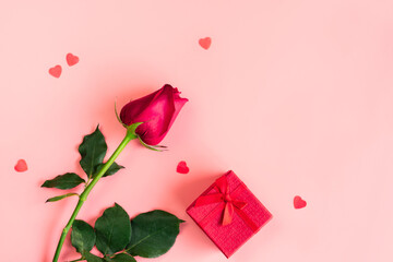 Flat lay of small hearts, red gift box and rose on pastel pink background. Valentines day, anniversary, birthday concept. Flat lay, top view copy space