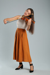 Beautiful woman playing violin on grey background