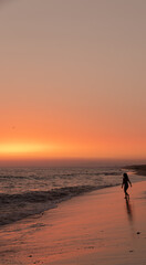 Fototapeta premium person walking on the beach at sunset