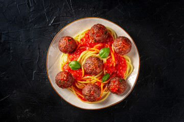 Meatballs with spaghetti, shot from the top on a black background