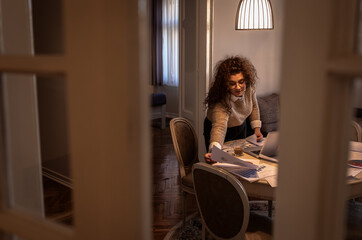 Young woman working at home while sitting at table in living room.