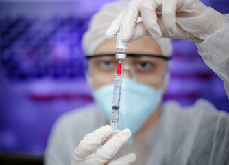 Medica segurando uma seringa de Vacina na prevenção de covid 19 com fundo obstrato e desfocado.