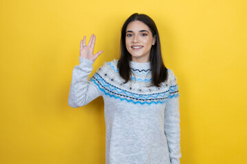Young caucasian woman wearing casual sweater over yellow background doing star trek freak symbol