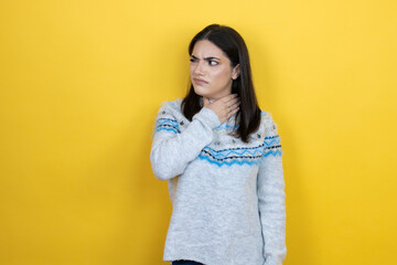 Young caucasian woman wearing casual sweater over yellow background touching painful neck, sore throat for flu, clod and infection