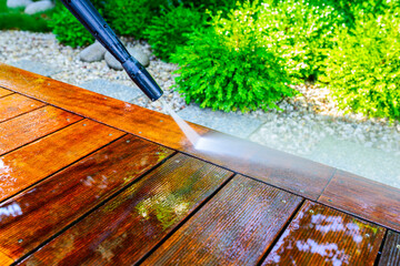 cleaning the terrace with a pressure washer - high-pressure cleaner on the wooden surface of the terrace - very shallow depth of field - sharpness on the terrace board under a stream of water - 411805230