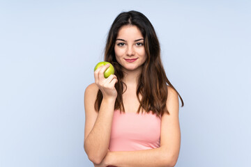 Young caucasian woman isolated on blue background with an apple