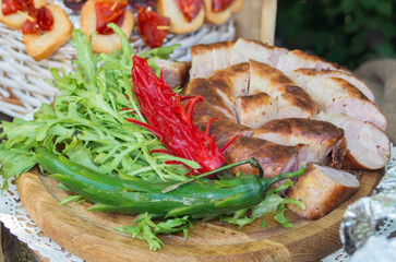 homemade sausage on a wooden board with a serving of greens and hot peppers