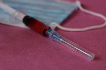 medicine vaccination syringe with medicine blood vial on a pink background