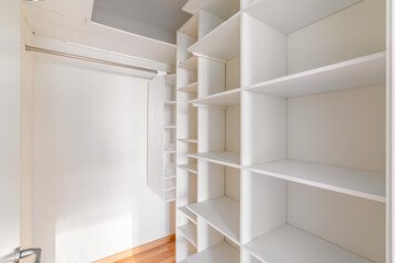 Fototapeta na wymiar Interior of small, white and empty dressing room with shelves and no clothes