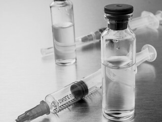 Syringes and ampoules on a polished metal background. Coronavirus vaccination and immunization...