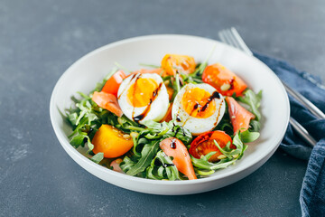 Healthy vegan salad of fresh tomato, arugula, salmon, egg and sesame on plate. Diet menu. Close-up