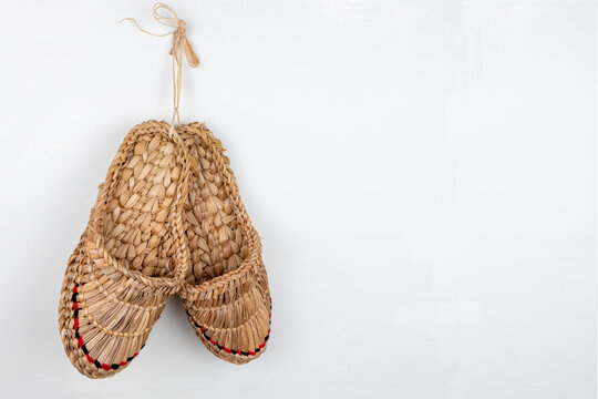 Russian bast shoes (Lapti) hanging on the white wall. Traditional peasant Russian shoes made with bast fibers.