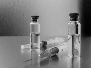 Syringes and ampoules on a polished metal background. Coronavirus vaccination and immunization...