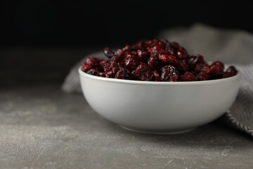 Bowl of dried cranberries on grey table, closeup
