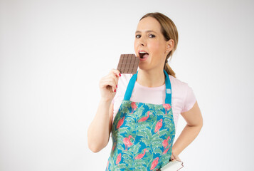 Smiling beautiful young woman wearing apron hold chocolate bar over white background.