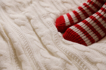 Woman in warm socks on knitted blanket, closeup. Space for text