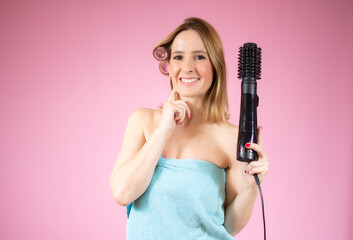 Portrait of young beautiful woman doing hairstyle over pink background.