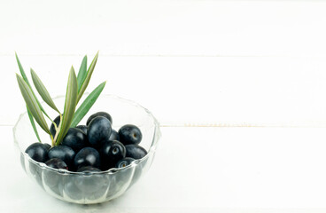 Olive branch with olives served in bowl on white background