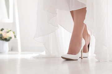 Young bride in beautiful wedding shoes walking indoors, closeup