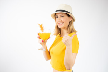 Beautiful young blonde woman in yellow t-shirt drinking orange juice in a summer day. Healthy organic drinks concept. People on a diet.