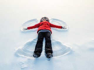 Fototapeta na wymiar Snow angel made by a happy woman in the snow. Top flat overhead view