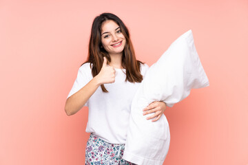 Young woman in pajamas isolated on pink background giving a thumbs up gesture