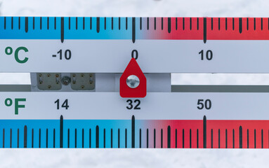Thermometer with horizontal scale. The thermometer shows 0 degrees Celsius and 32 degrees Fahrenheit. Background - white snow. Melting point of H2O concept.