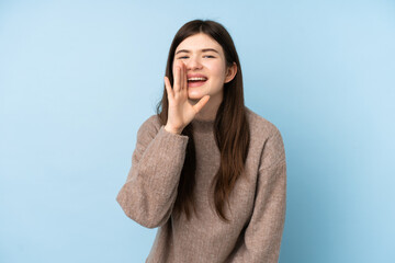 Young Ukrainian teenager girl wearing a sweater over isolated blue background shouting with mouth wide open