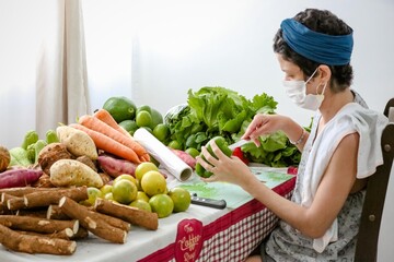 Verduras e legumes sendo cortadas em rodelas por uma mulher na mesa com uma faca apontada e fundo obstrato desfocado.