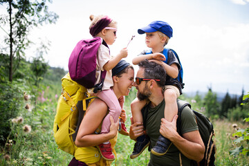 Family with small children hiking outdoors in summer nature.